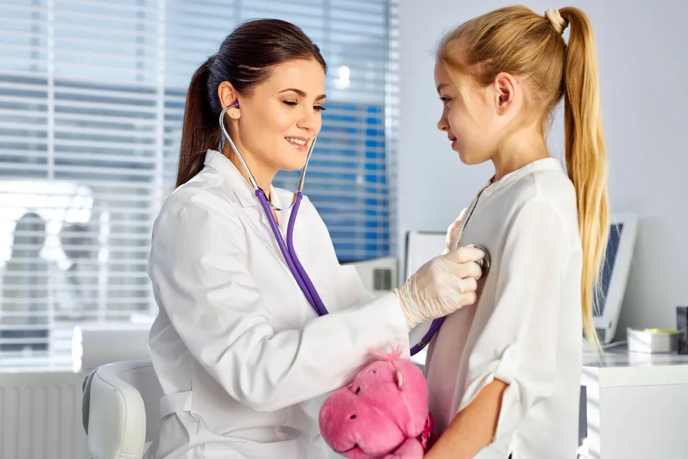 A pediatrician listening to a girl’s heartbeat with a stethoscope